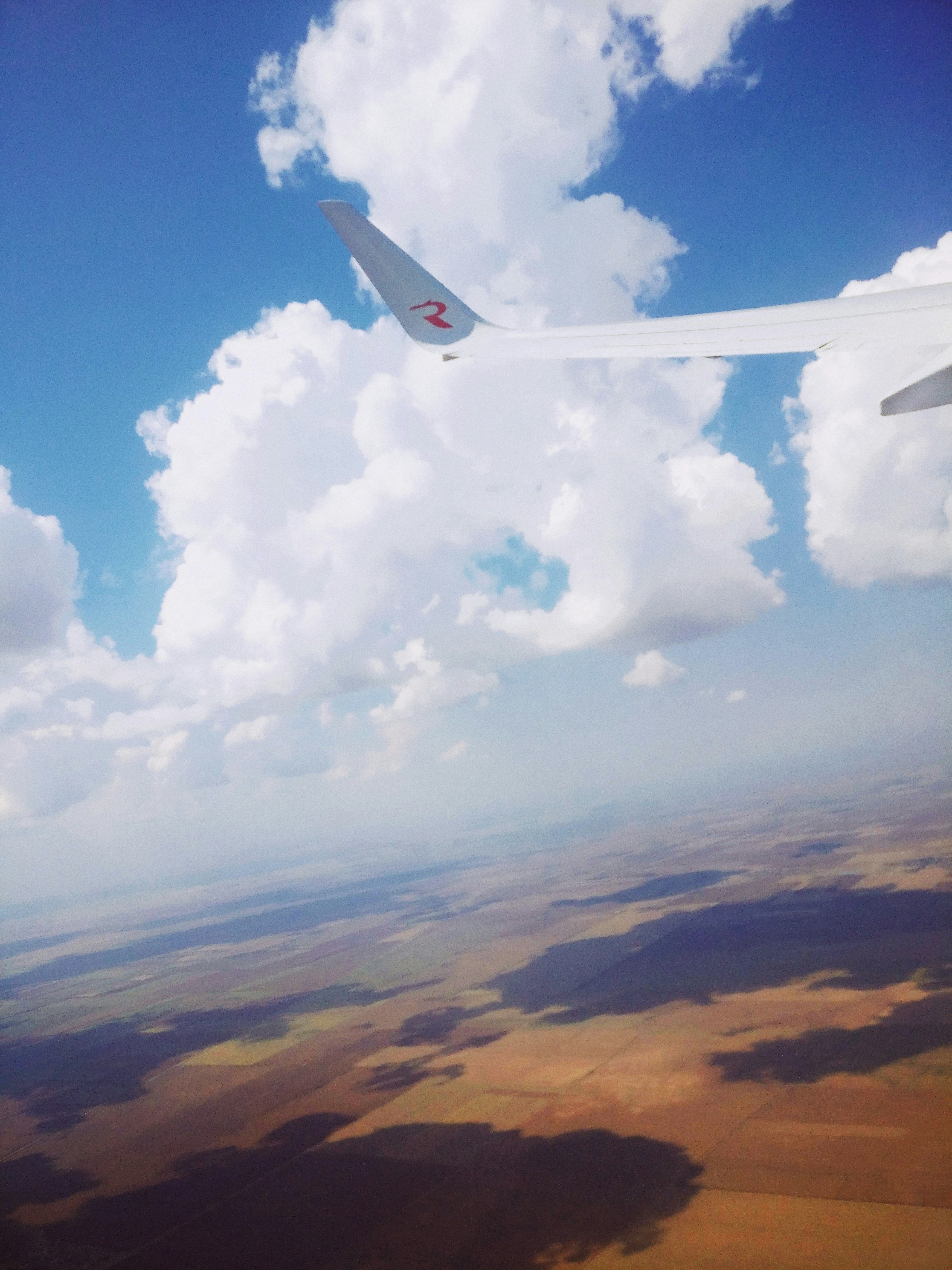 white and blue airplane flying over white clouds during daytime